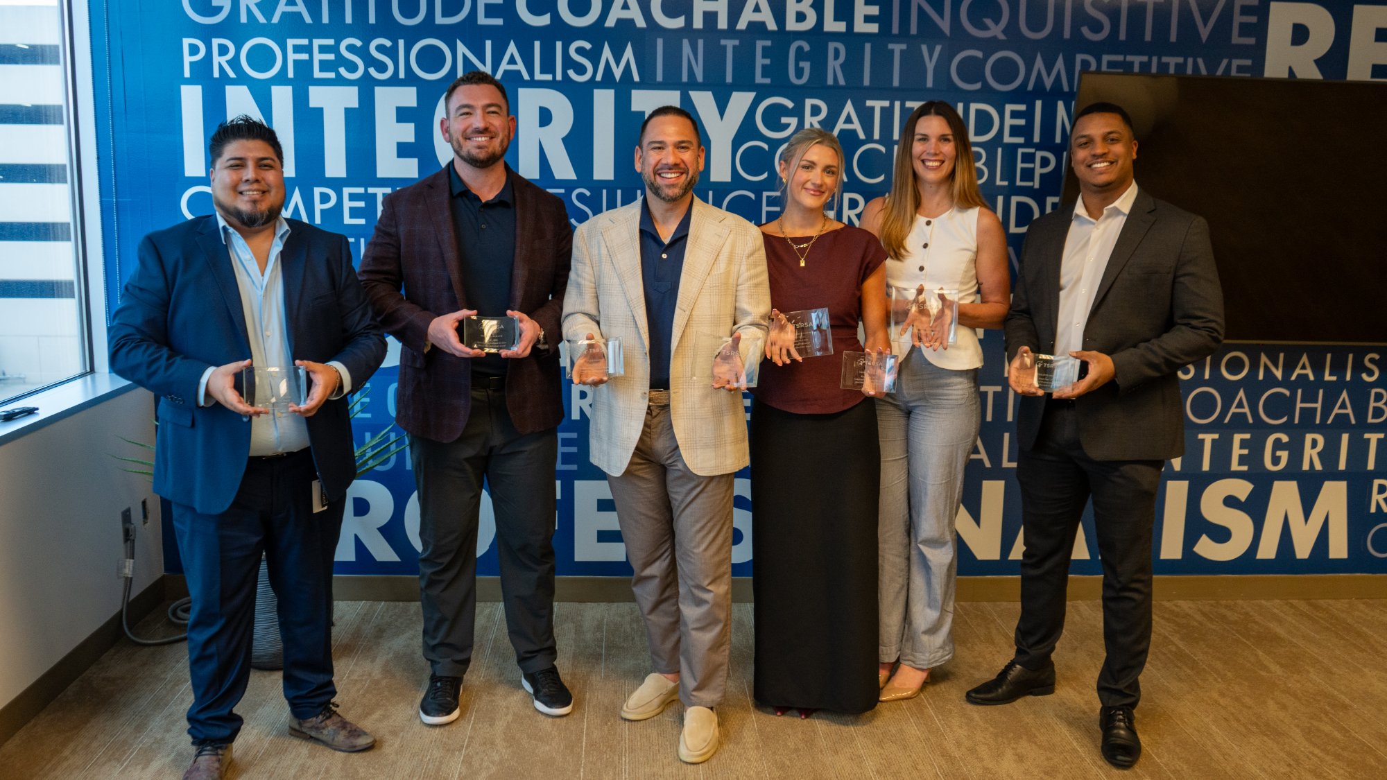 Encore Search Partners top producers holding their awards in front of the company values wall